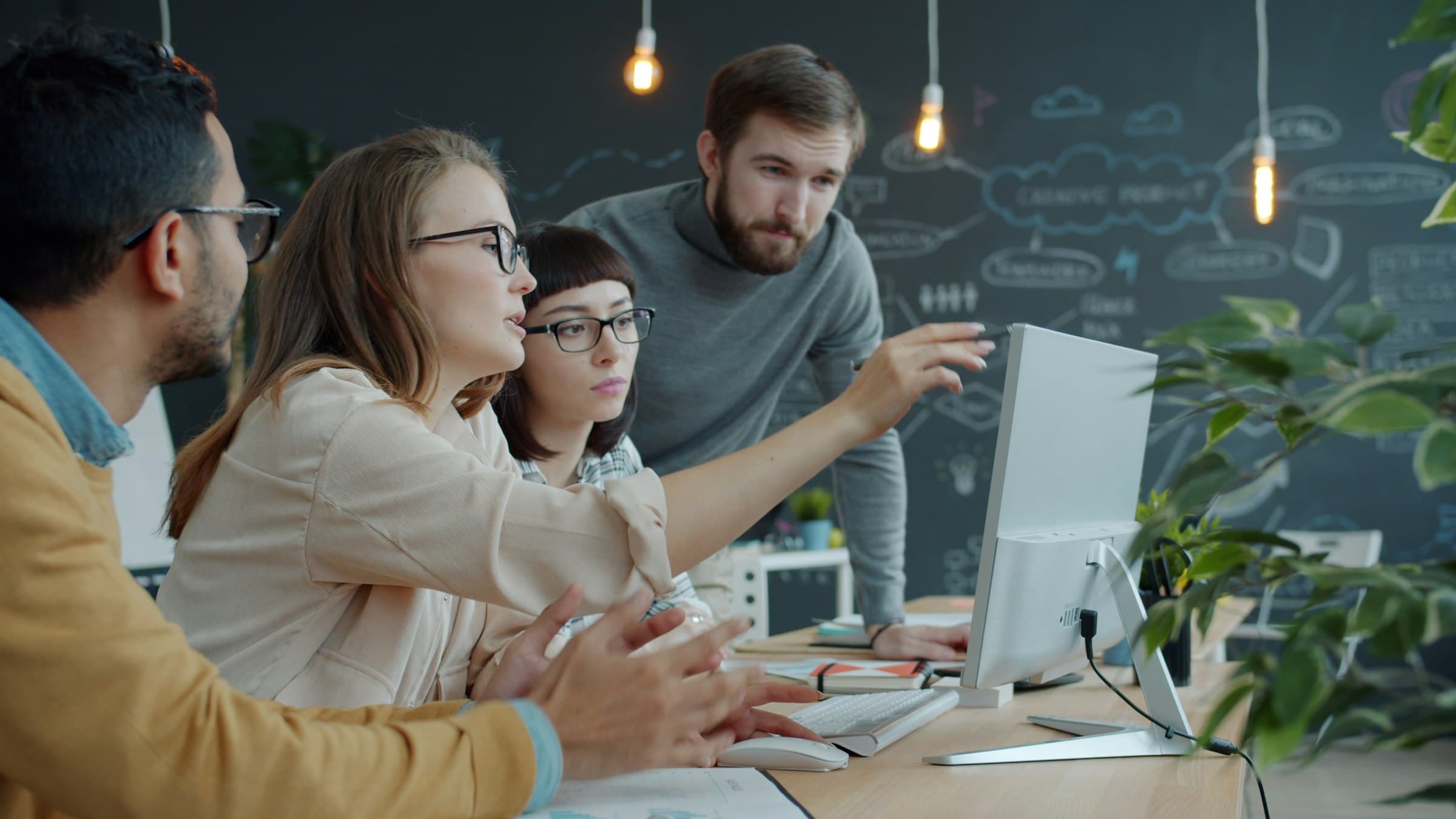 Software engineers collaborating around a workstation in a modern office